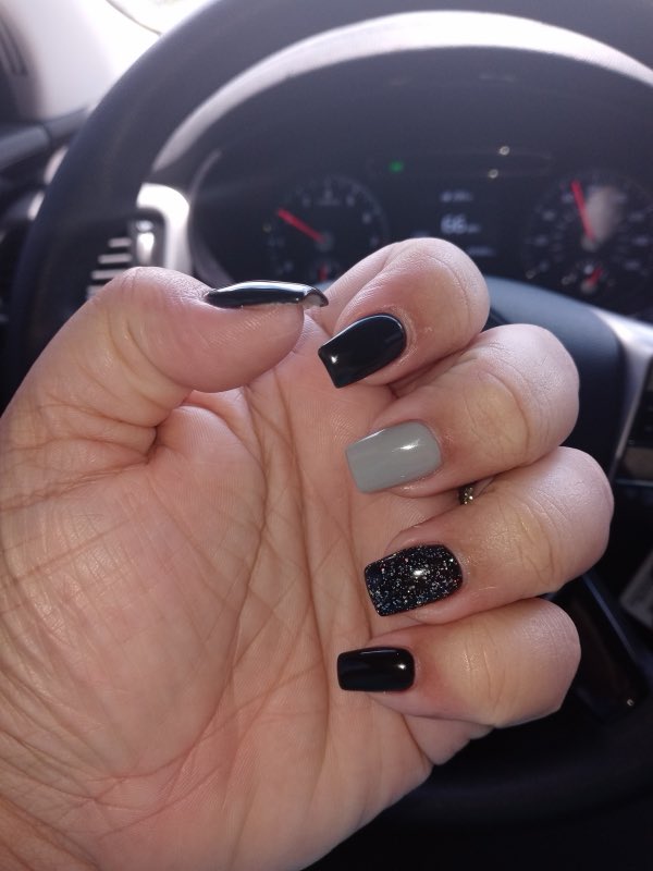 A finished gel manicure in black, grey and glitter